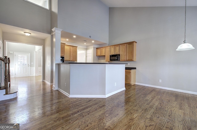 kitchen featuring kitchen peninsula, a towering ceiling, dark hardwood / wood-style floors, and decorative light fixtures