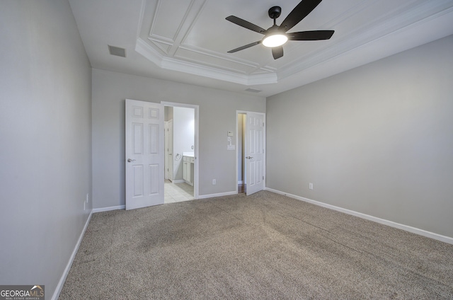 unfurnished bedroom featuring ceiling fan, a raised ceiling, ensuite bathroom, and light carpet