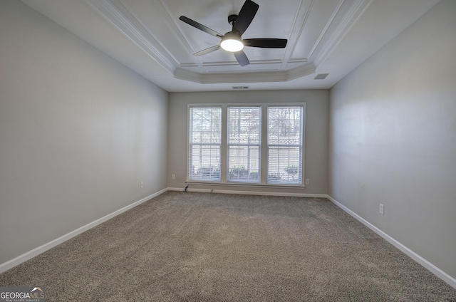 carpeted spare room featuring a raised ceiling, ceiling fan, and ornamental molding