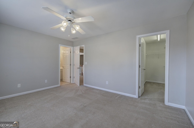 unfurnished bedroom with ceiling fan, a walk in closet, light carpet, and a closet