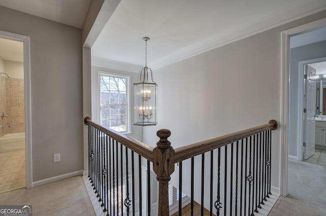 hall with light colored carpet, an inviting chandelier, and ornamental molding