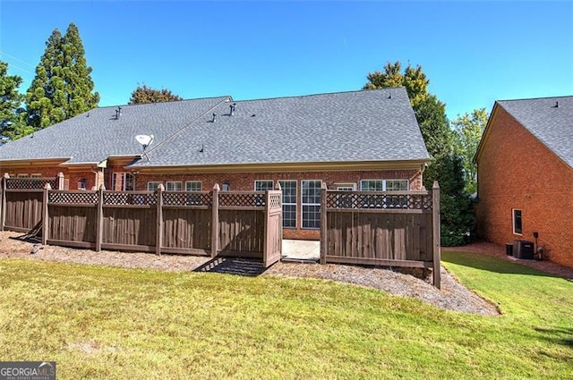 rear view of property with a lawn and central AC unit