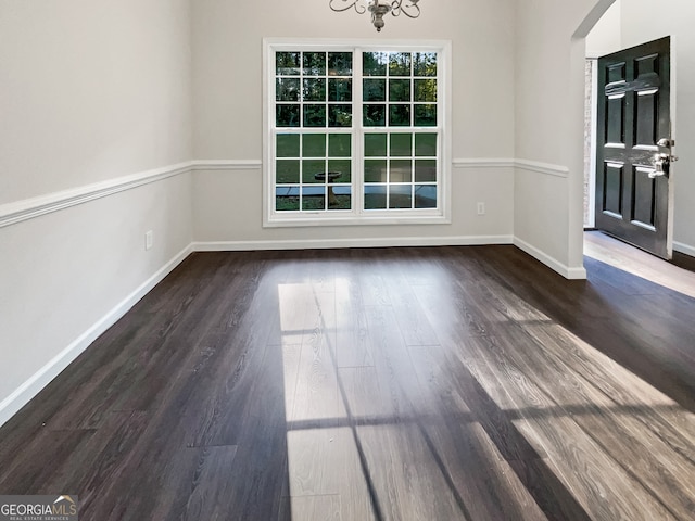 unfurnished dining area with a notable chandelier and dark hardwood / wood-style flooring