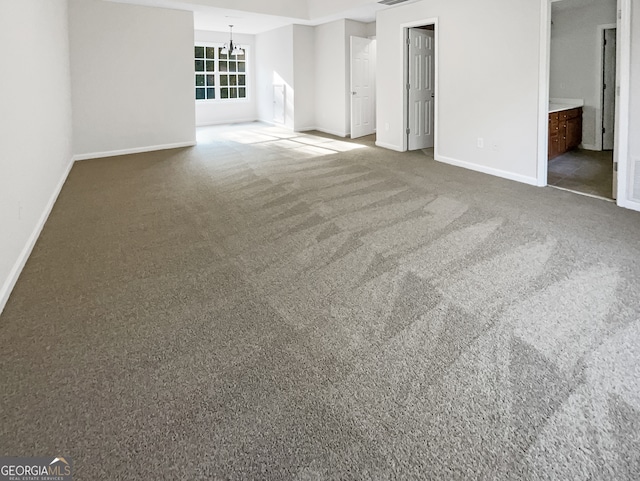 carpeted empty room featuring a notable chandelier