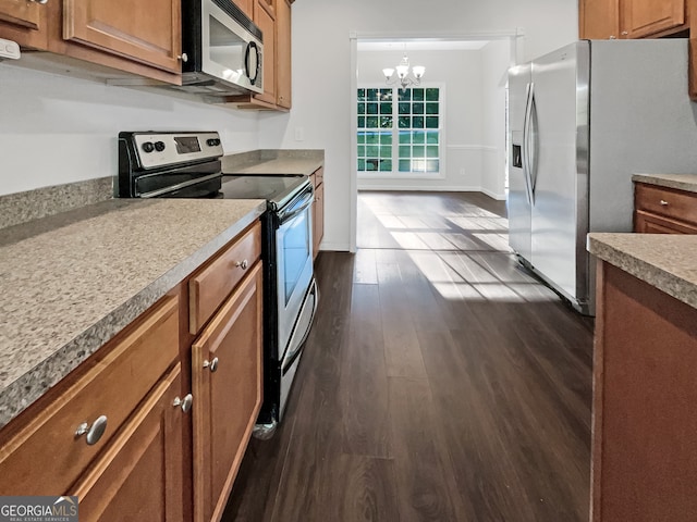 kitchen with an inviting chandelier, stainless steel appliances, hanging light fixtures, and dark hardwood / wood-style flooring