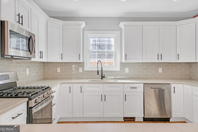 kitchen with sink, white cabinets, stainless steel appliances, and backsplash