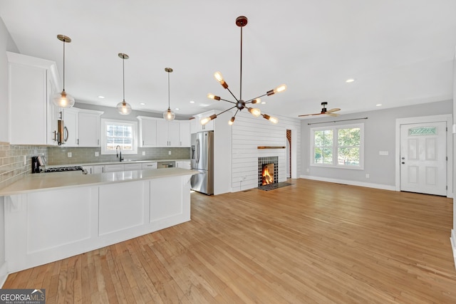 kitchen with appliances with stainless steel finishes, a brick fireplace, light wood-type flooring, and plenty of natural light