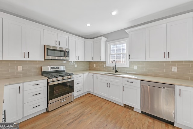 kitchen with white cabinetry, stainless steel appliances, light hardwood / wood-style flooring, and sink