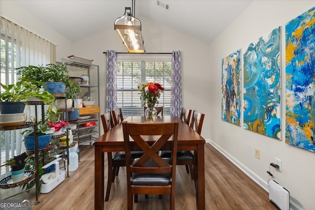 dining room with wood-type flooring and lofted ceiling