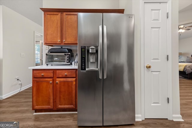 kitchen featuring stainless steel refrigerator with ice dispenser, dark wood-type flooring, and ceiling fan