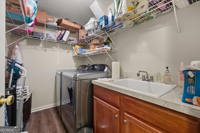 laundry room featuring dark hardwood / wood-style floors, sink, separate washer and dryer, cabinets, and a textured ceiling