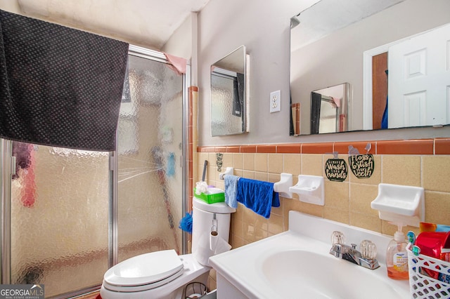 bathroom with vanity, toilet, tile walls, and a shower with shower door