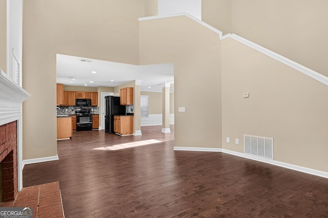 unfurnished living room with dark wood-type flooring, a high ceiling, and a fireplace