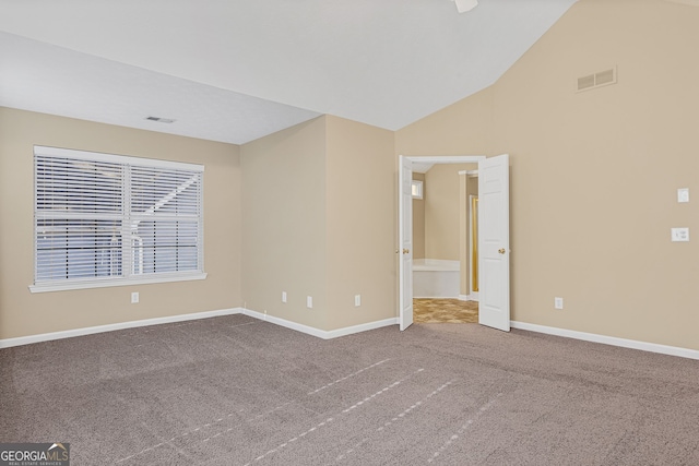 carpeted empty room with high vaulted ceiling