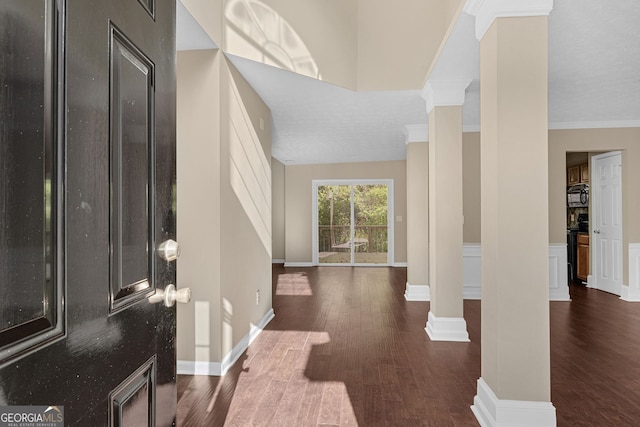 foyer featuring crown molding, ornate columns, and dark hardwood / wood-style flooring