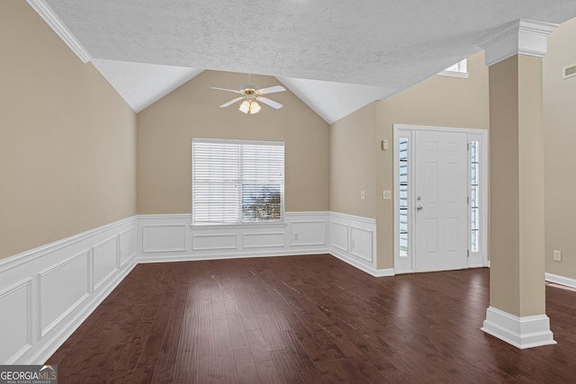 entrance foyer featuring a textured ceiling, decorative columns, dark hardwood / wood-style flooring, ceiling fan, and lofted ceiling