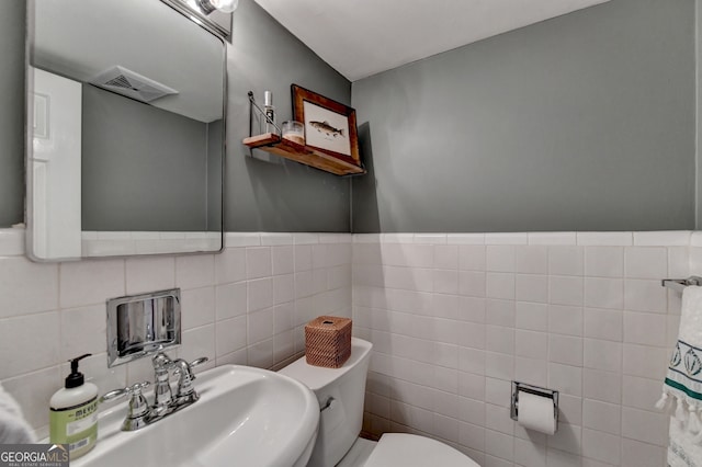 bathroom featuring tile walls, sink, and toilet