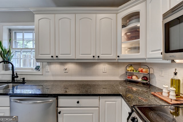 kitchen with sink, backsplash, stainless steel appliances, white cabinets, and dark stone countertops