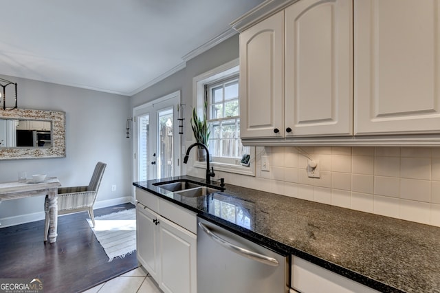 kitchen featuring sink, light hardwood / wood-style floors, dark stone counters, stainless steel dishwasher, and white cabinets