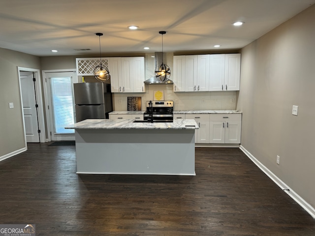 kitchen with an island with sink, appliances with stainless steel finishes, white cabinetry, wall chimney exhaust hood, and decorative light fixtures