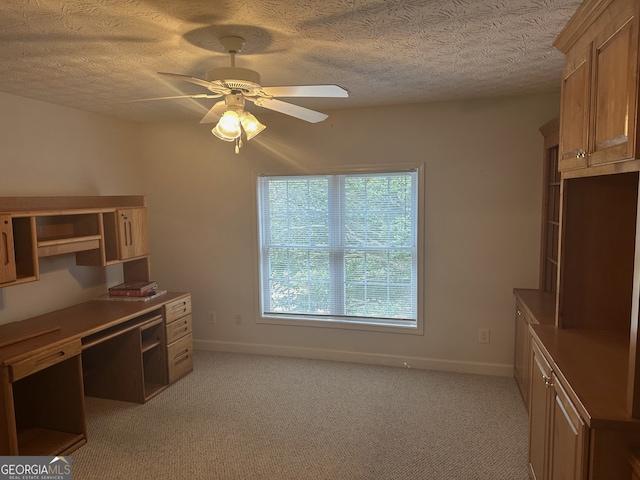 unfurnished office featuring light carpet, a textured ceiling, and ceiling fan