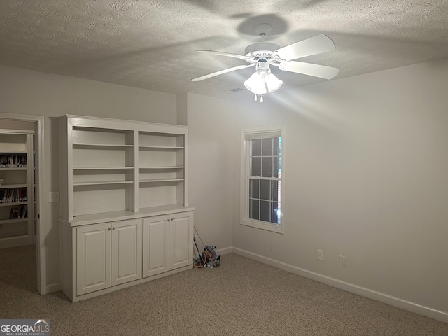 carpeted spare room featuring a textured ceiling and ceiling fan