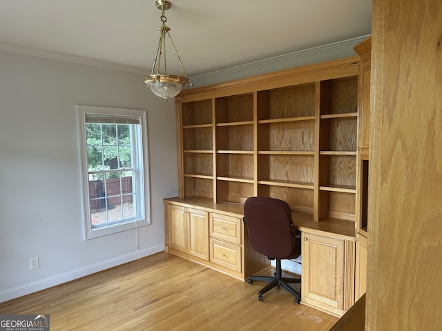 unfurnished office featuring built in desk, ornamental molding, and light hardwood / wood-style floors