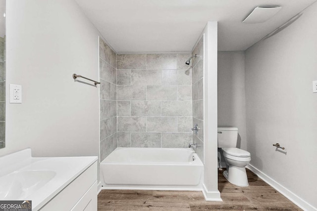 full bathroom featuring toilet, hardwood / wood-style floors, tiled shower / bath combo, and vanity