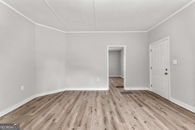 spare room with ornamental molding and light hardwood / wood-style flooring