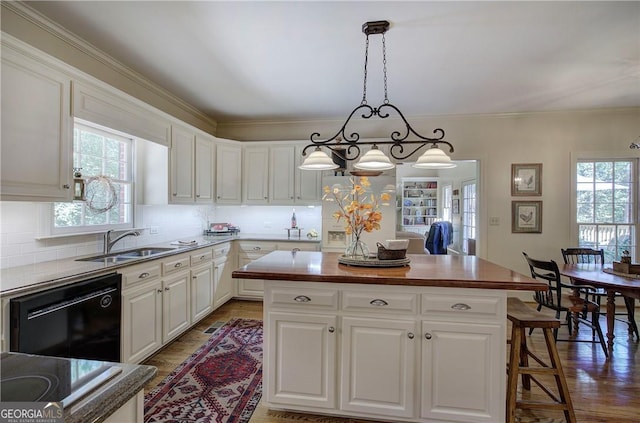 kitchen featuring a kitchen island, black dishwasher, hanging light fixtures, wood-type flooring, and white cabinets