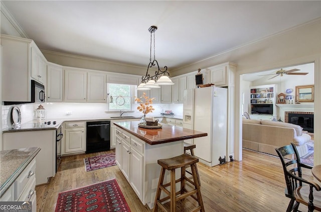 kitchen featuring sink, black appliances, a center island, white cabinets, and light hardwood / wood-style floors