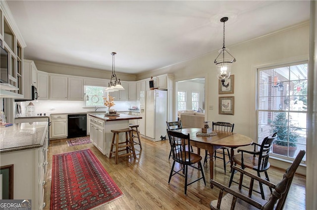 kitchen with light hardwood / wood-style floors, black appliances, a center island, and decorative light fixtures