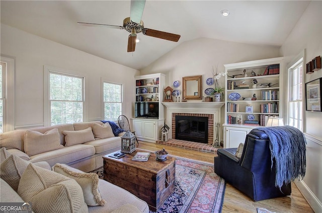 living room with ceiling fan, lofted ceiling, light wood-type flooring, and a fireplace