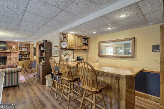 bar featuring butcher block counters, a paneled ceiling, dark wood-type flooring, built in shelves, and a fireplace