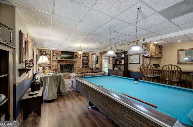 rec room with dark hardwood / wood-style flooring, a drop ceiling, billiards, and a brick fireplace