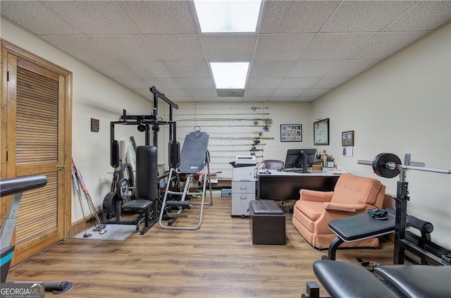 exercise room with a drop ceiling and light wood-type flooring