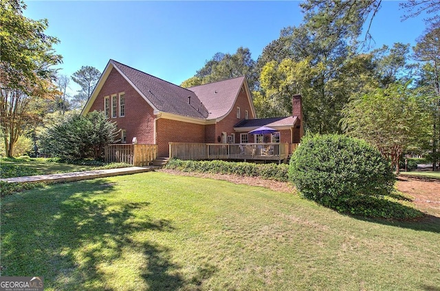 rear view of property with a wooden deck and a lawn