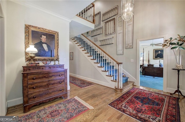 stairway with crown molding, hardwood / wood-style flooring, and ceiling fan