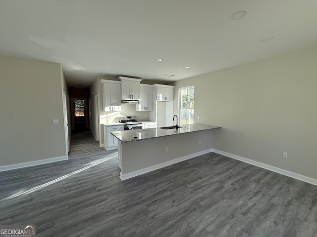 kitchen with light stone countertops, sink, electric range, white cabinetry, and dark wood-type flooring