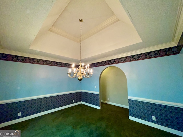 unfurnished dining area featuring a textured ceiling, a chandelier, a tray ceiling, dark carpet, and crown molding