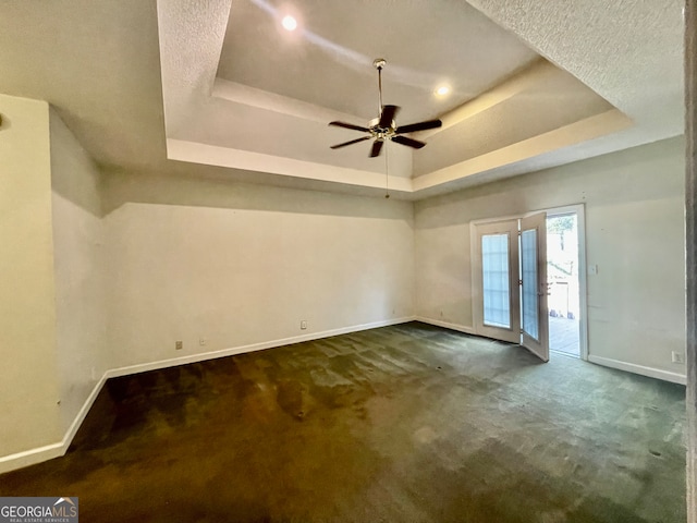 carpeted spare room featuring ceiling fan, a textured ceiling, and a tray ceiling