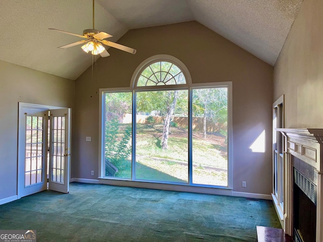 unfurnished living room with ceiling fan, a textured ceiling, vaulted ceiling, and dark colored carpet