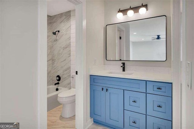 full bathroom featuring tiled shower / bath, vanity, and toilet