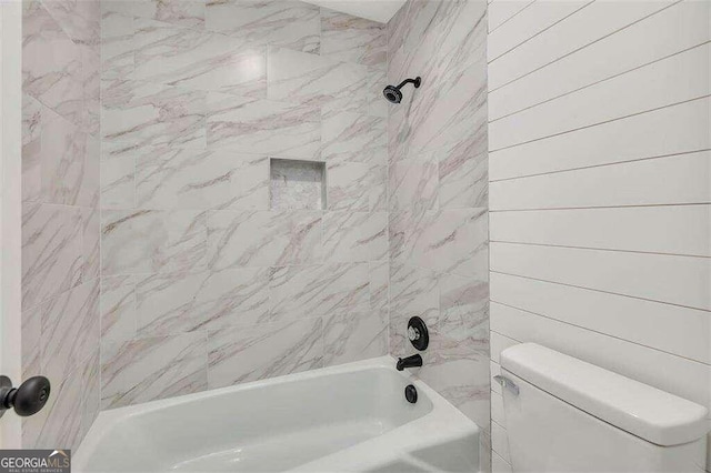 bathroom featuring tiled shower / bath and toilet