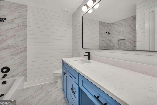 full bathroom featuring vanity, tiled shower / bath, and toilet