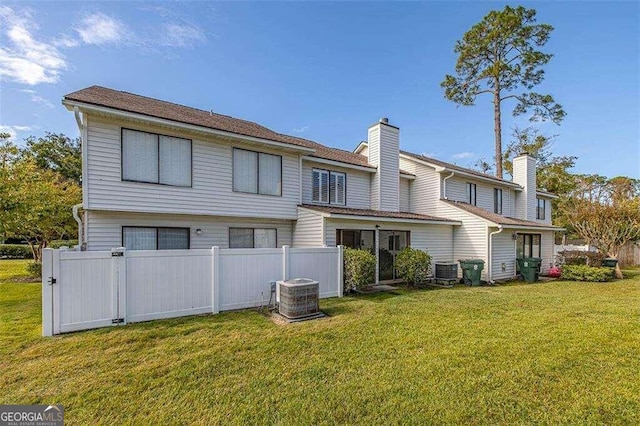 rear view of property with a yard and central AC