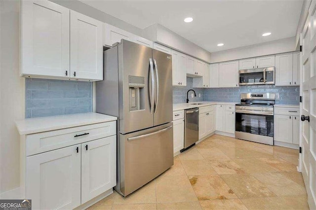 kitchen featuring backsplash, sink, appliances with stainless steel finishes, and white cabinets