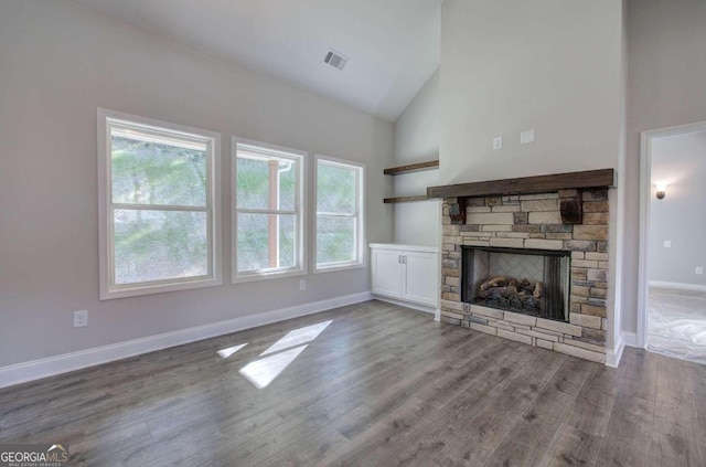 unfurnished living room featuring a stone fireplace, hardwood / wood-style floors, and high vaulted ceiling