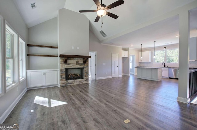 unfurnished living room featuring ceiling fan, sink, a fireplace, and hardwood / wood-style floors