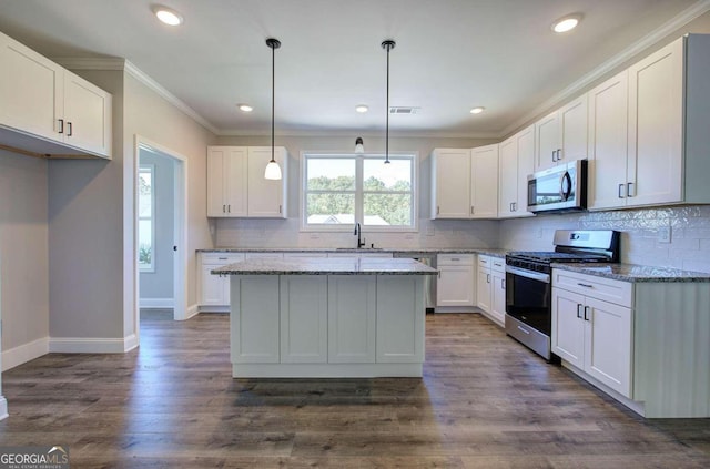 kitchen with dark hardwood / wood-style floors, appliances with stainless steel finishes, decorative light fixtures, and white cabinets